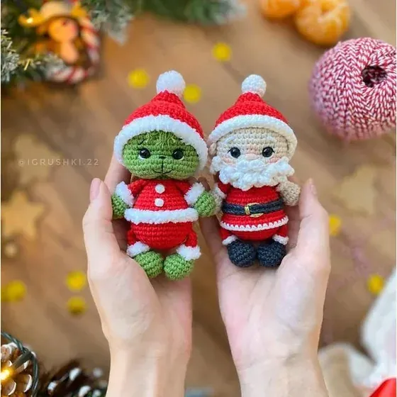 Dos muñequitos con gorro de Santa en la palma de las manos